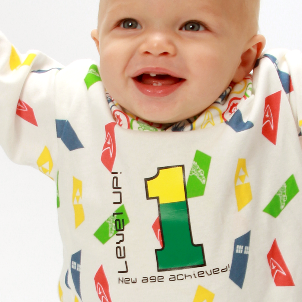 White-presenting baby of color. His outfit has a large 1 with the text "Level UP! New age achieved!"