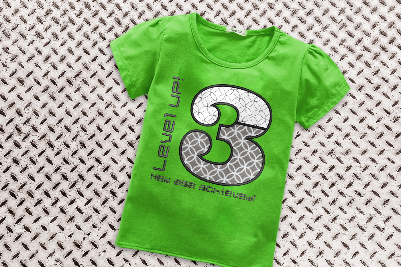 Shirt with large applique 3. Around the number is embroidered "Level UP! New age achieved!"