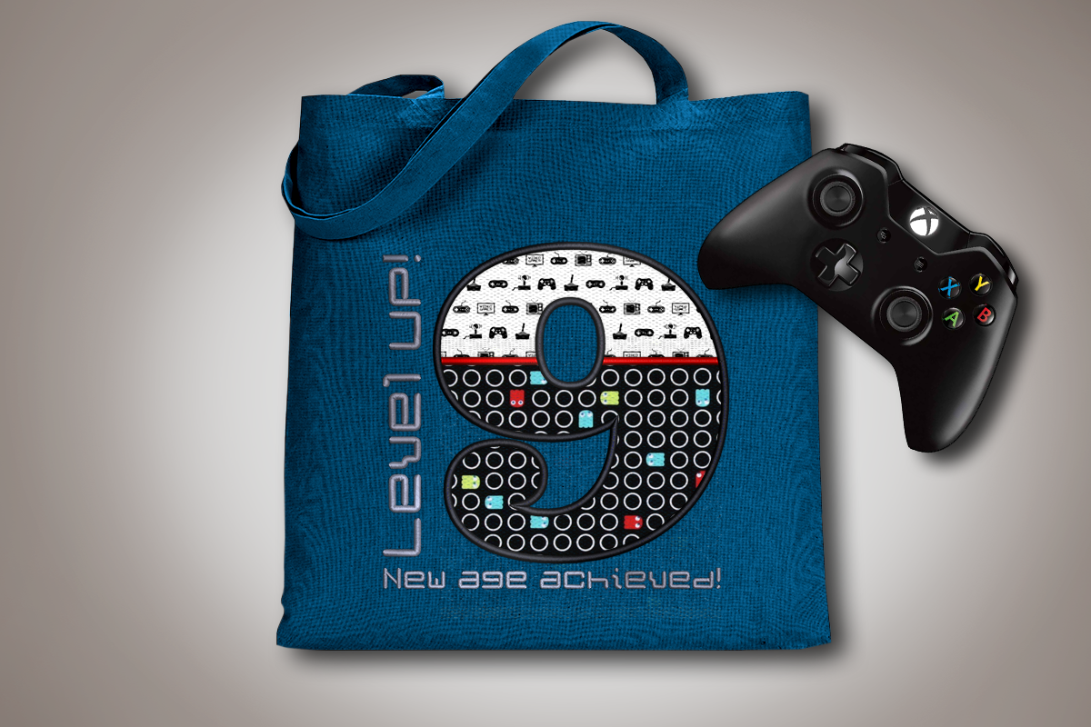 Tote bag with large applique 9. Around the number is embroidered "Level UP! New age achieved!"