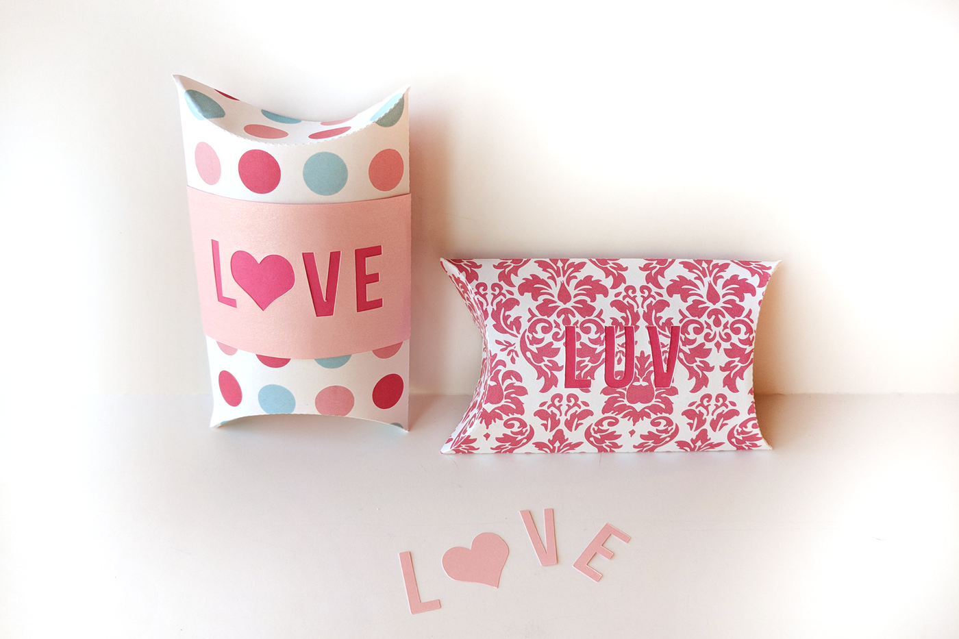 Two pillow boxes. One has a band that says LOVE with a heart for the O, the other says LUV.