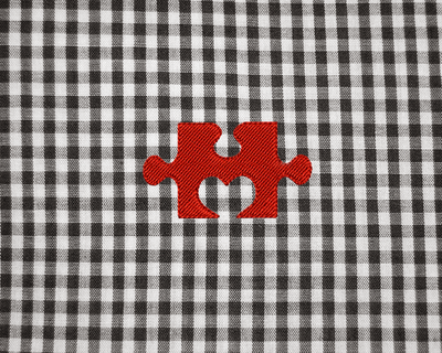 Embroidery of a puzzle piece with a heart shaped notch.