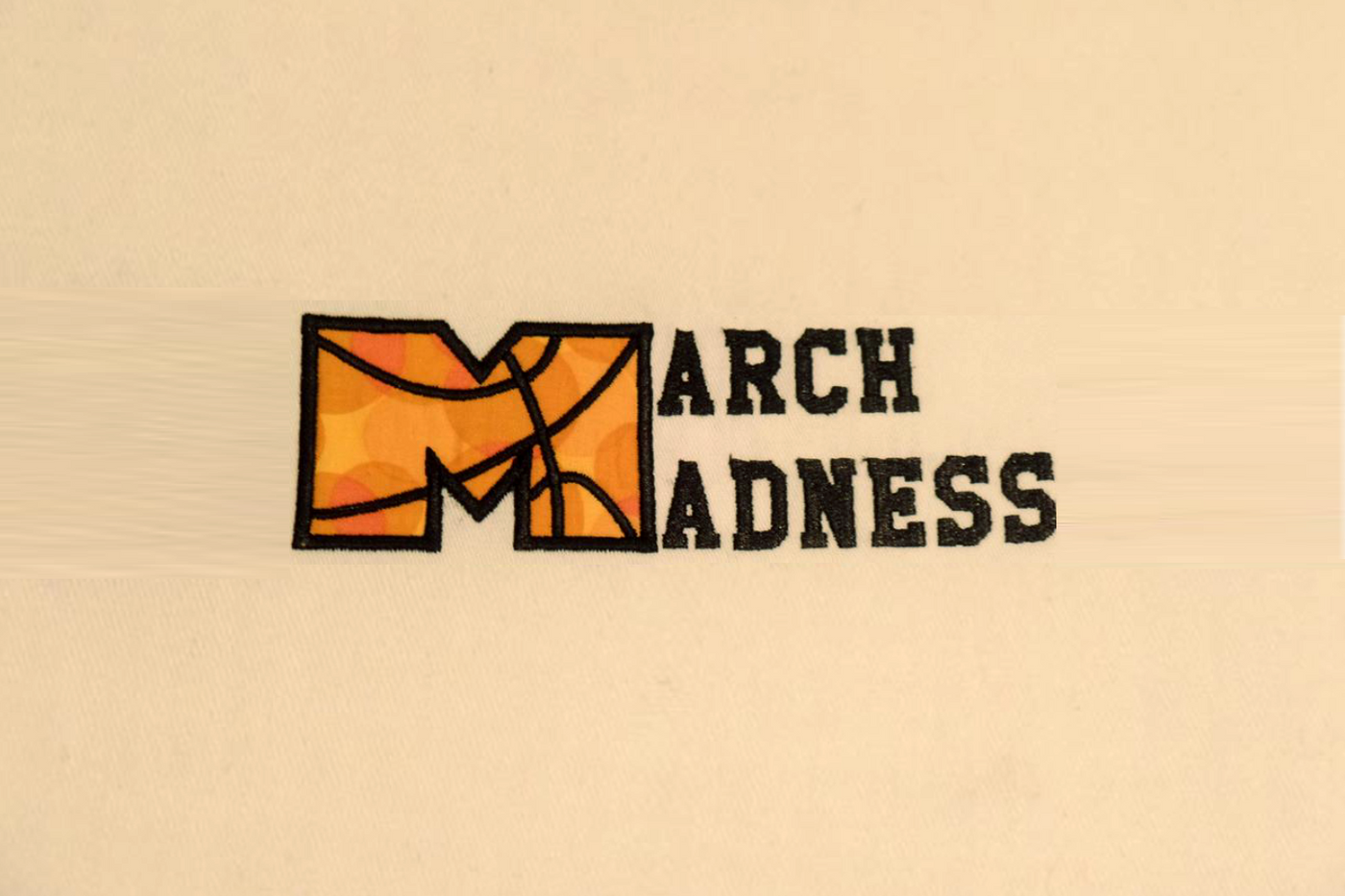 Applique that says "March Madness." The M has lines added to look like a basketball