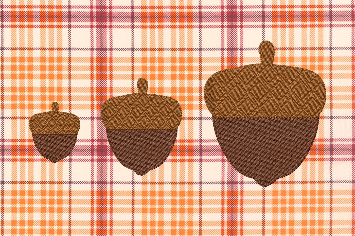 Three embroidered acorns of various sizes on a plaid background in fall colors. The acorn caps have a waffled embroidery texture.