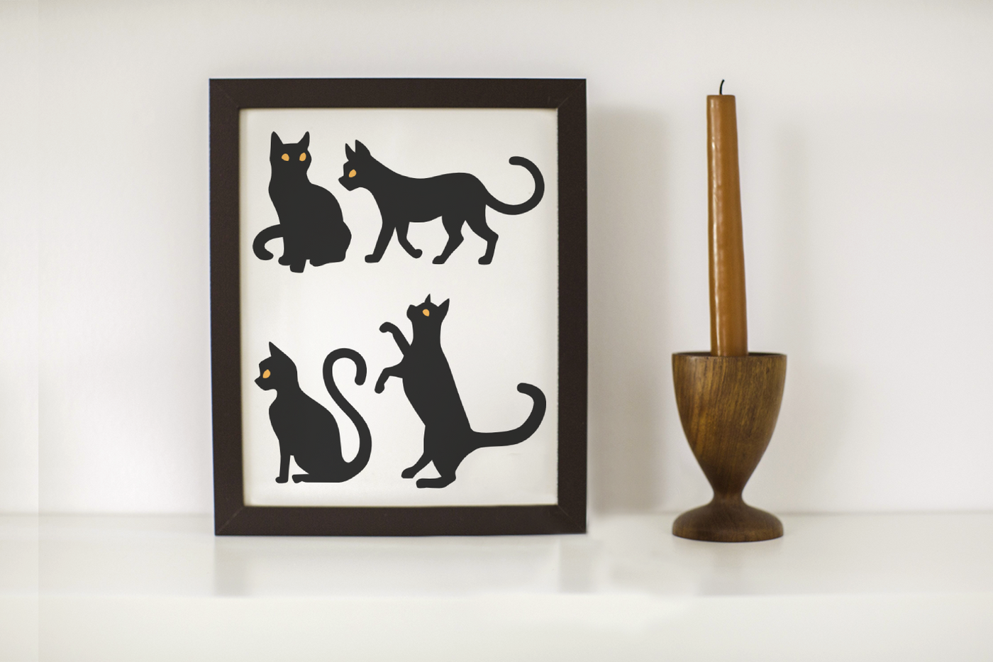 Framed poster of 4 minimal cat silhouettes with yellow eyes