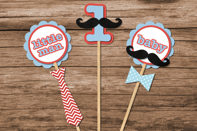 Mustache bash themed party centerpieces on sticks. One says "little man" with a tie, one has a number 1 with a mustache, and one says "baby" with a mustache and bow tie.