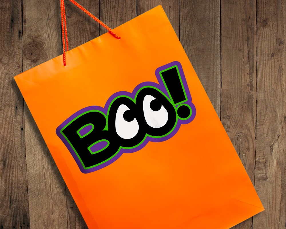 An orange gift bag on a wood surface with the word "BOO!" in black, white, green, and purple. The Os look like eyes.