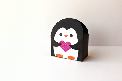 Penguin shaped gift box SVG design. The penguin holds a heart.