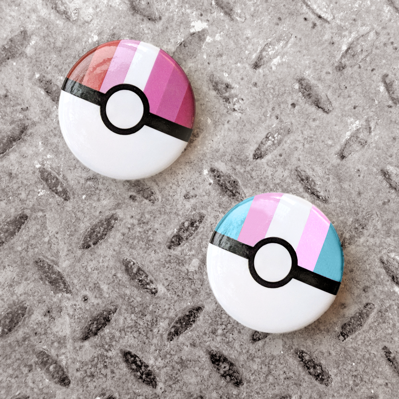 Two pins. Each is white on the bottom with a black horizontal stripe. The top half has vertical stripes in pride flag colors.