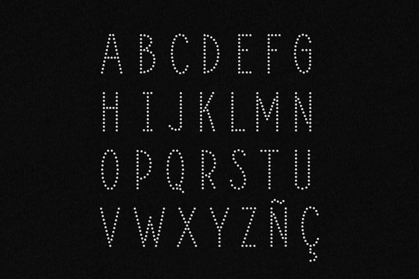 Art deco style alphabet made out of clear rhinestones on a black background.