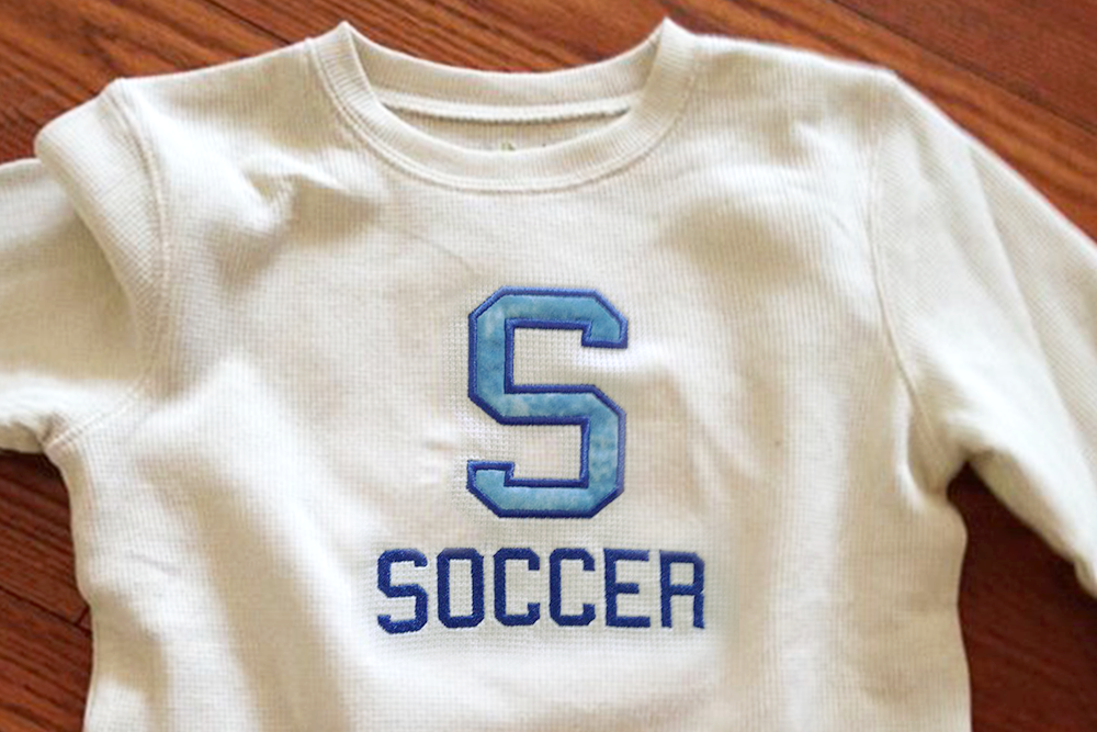 Applique S with the embroidered word "Soccer" below