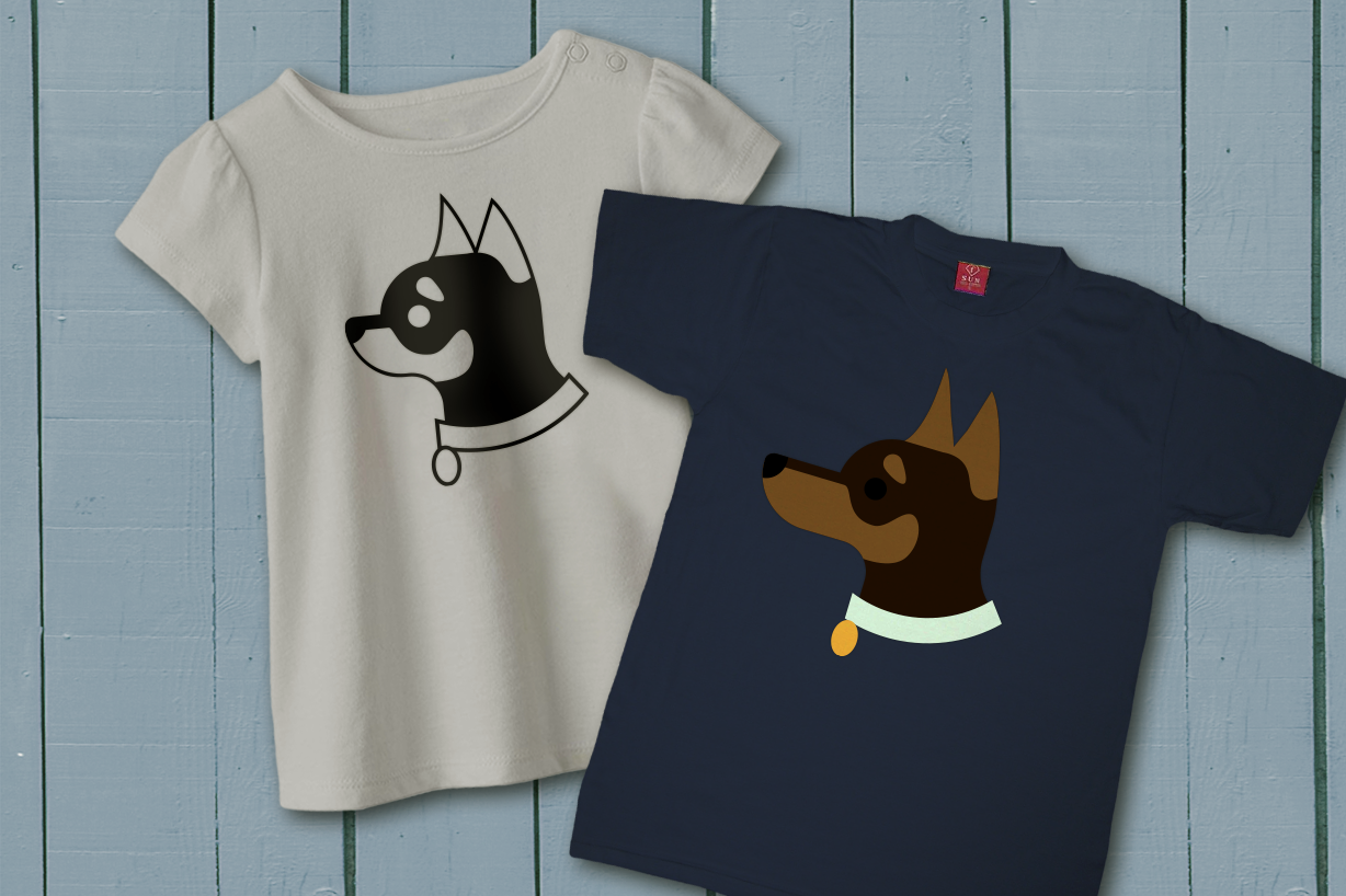 Two shirts lay on a blue painted wood background. Each features a dog in profile from the neck up with a collar. The dogs have black and tan markings. One has a long snout, like a min pin, and the other has a short snout like a chihuahua.