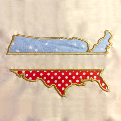 Applique US map with a split the middle. The stitching is gold. The top fabric is pale blue with white stars, the bottom fabric is red with white polkadots. It is embroidered onto a piece of off-white fabric.