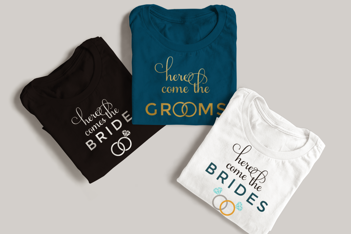 Three folded tees. They say "Here comes the Bride," Here come the Grooms," and "here come the Brides" with rings incorporated into the design.