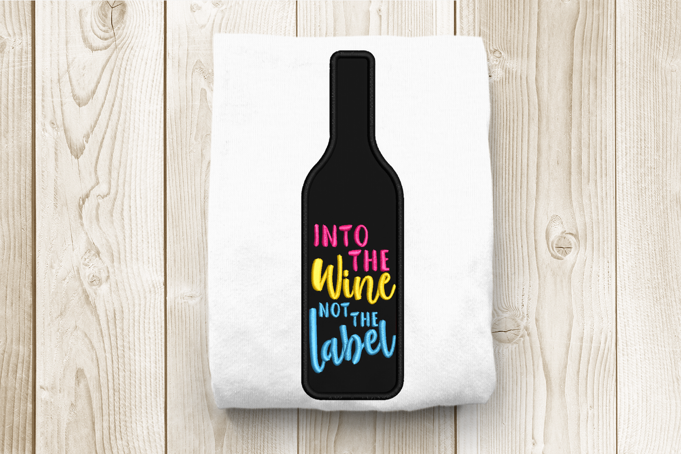 Wine bottle applique design that says "into the wine not the label"