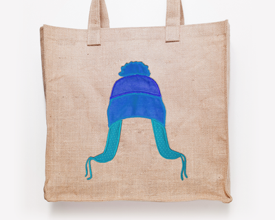 Tote bag with an applique design of a tri-colored winter hat with flaps and a pom pom