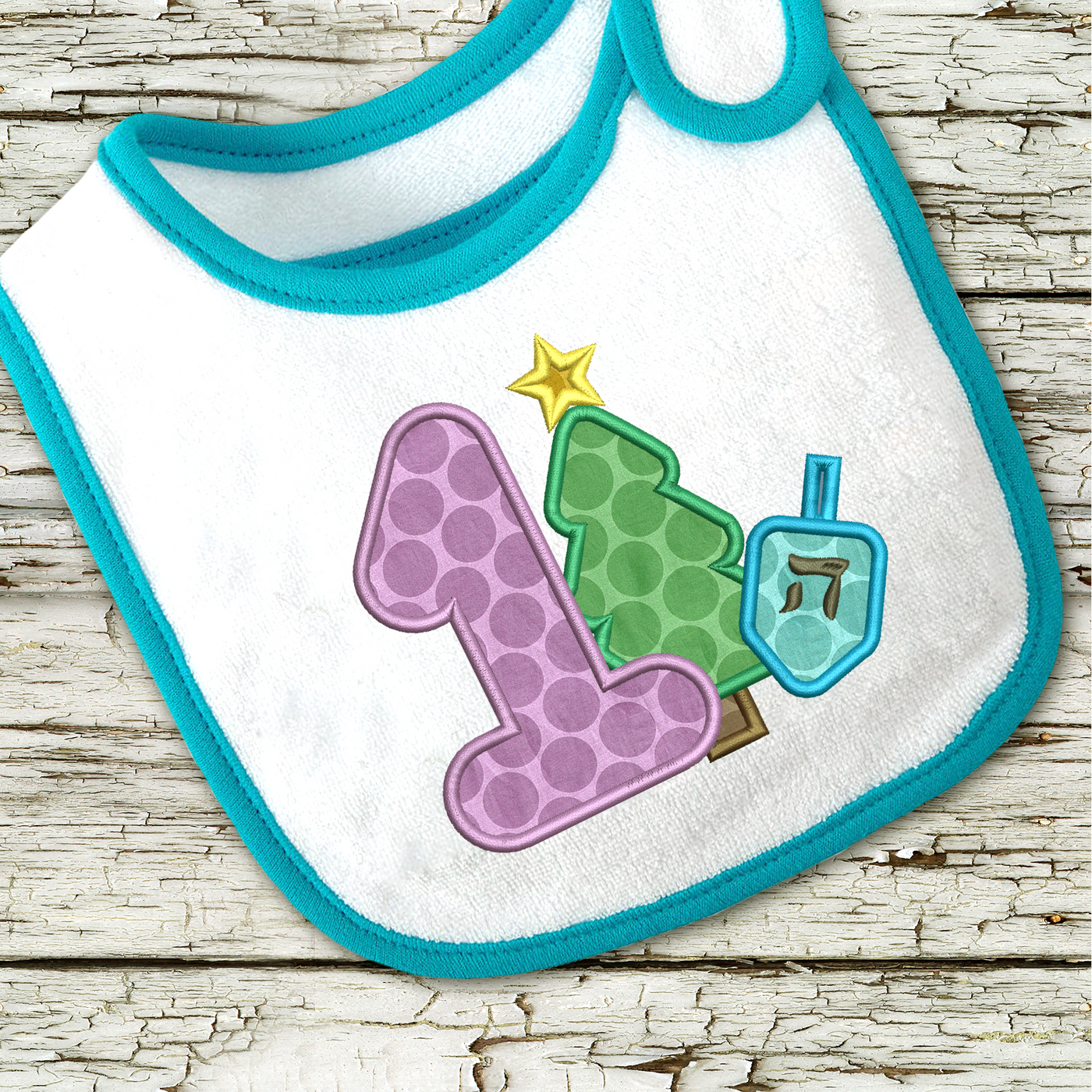 Bib with applique design of a large 1 and a Christmas tree and dreidel.