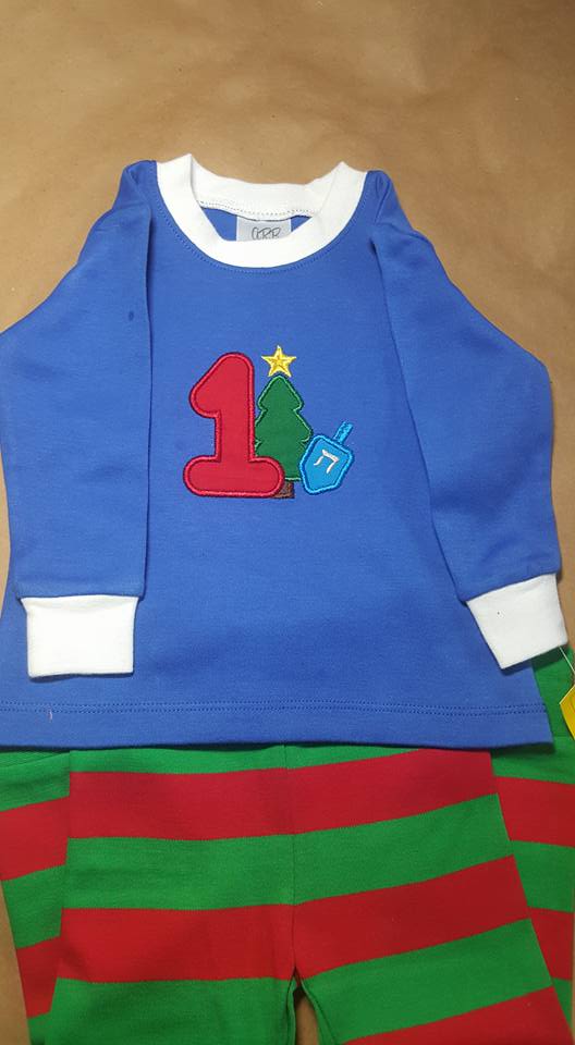 Holiday jammies with an applique design of a 1 and a Christmas tree and dreidel.