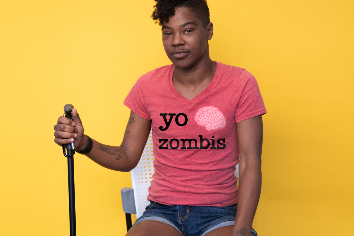 Nonbinary black person with a cane in a shirt that says "yo [brain] zombis"