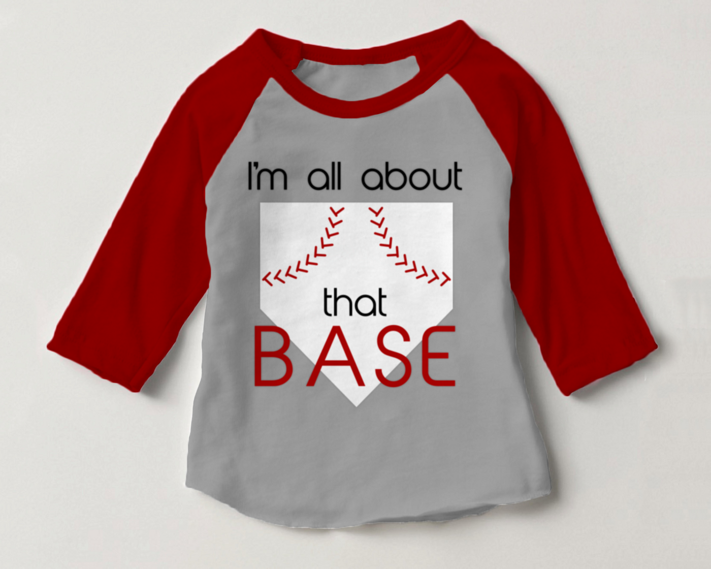 Raglan tee with a design that has a home plate with red stitching like a baseball. Text says "I'm all about that base."