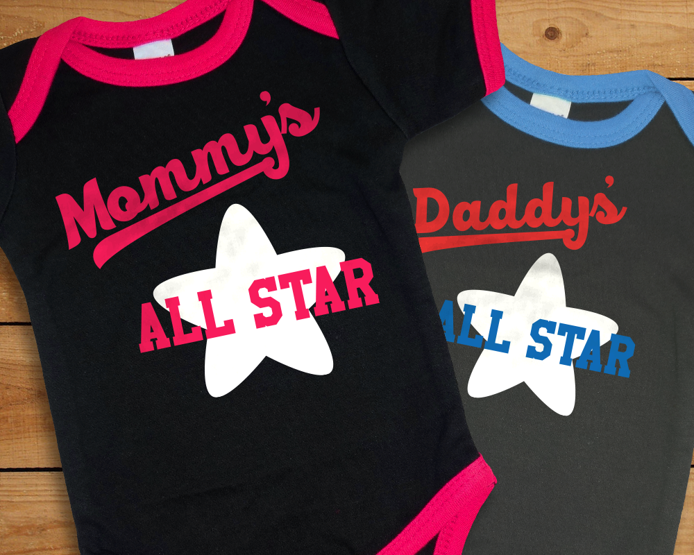 Two ringer baby onesies, one in black with pink trim, the other charcoal with blue trim. They say "Mommy's All Star" and "Daddy's All Star" with a star behind.