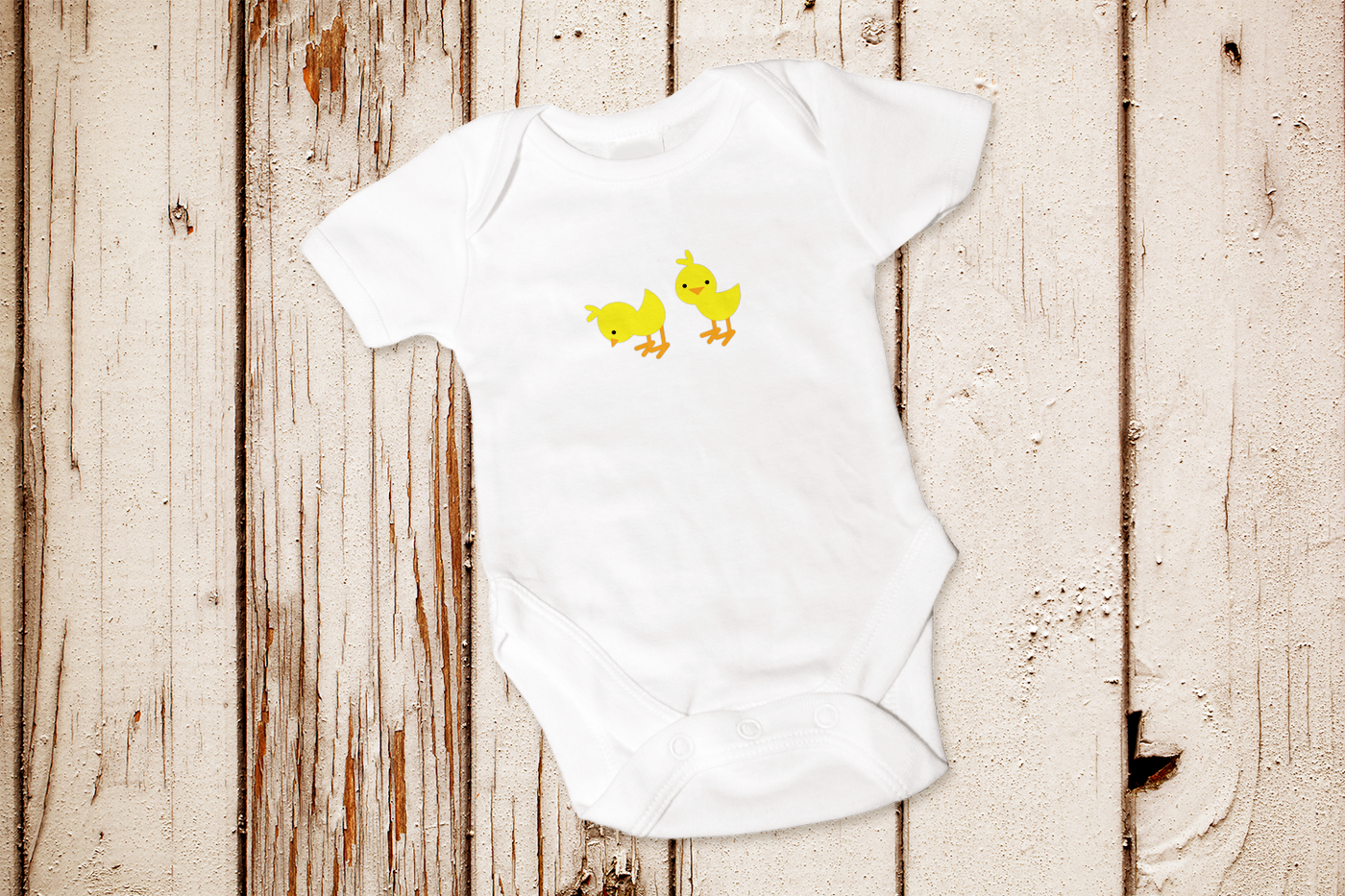 A white baby onesie with two baby chicks.