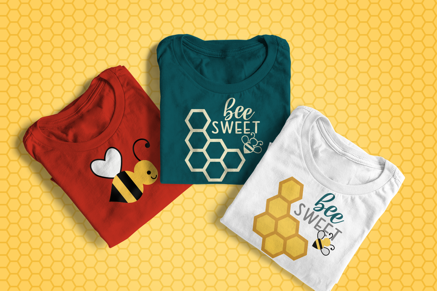 Three folded shirts on a honeycomb pattern background. On shirt has a cartoon smiling bee. The other two shirts have a honeycomb, a simple bee, and the words "bee sweet." One is done as a single color design, the other is done in multiple colors.