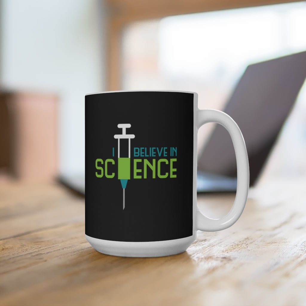 Mug with a design that says "I believe in science" with a syringe. Mug is on a desk.