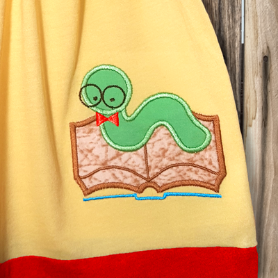 Applique worm crawling on a book and wearing glasses and a bow tie.