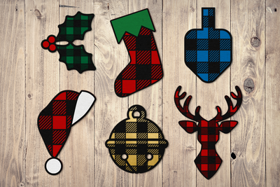 6 holiday icons made out of paper with a buffalo plaid pattern: holly, stocking, dreidel, santa hat, round bell, reindeer bust