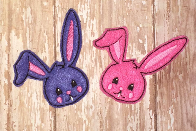 Purple and pink Easter bunny face felties with one ear partially flopped down.