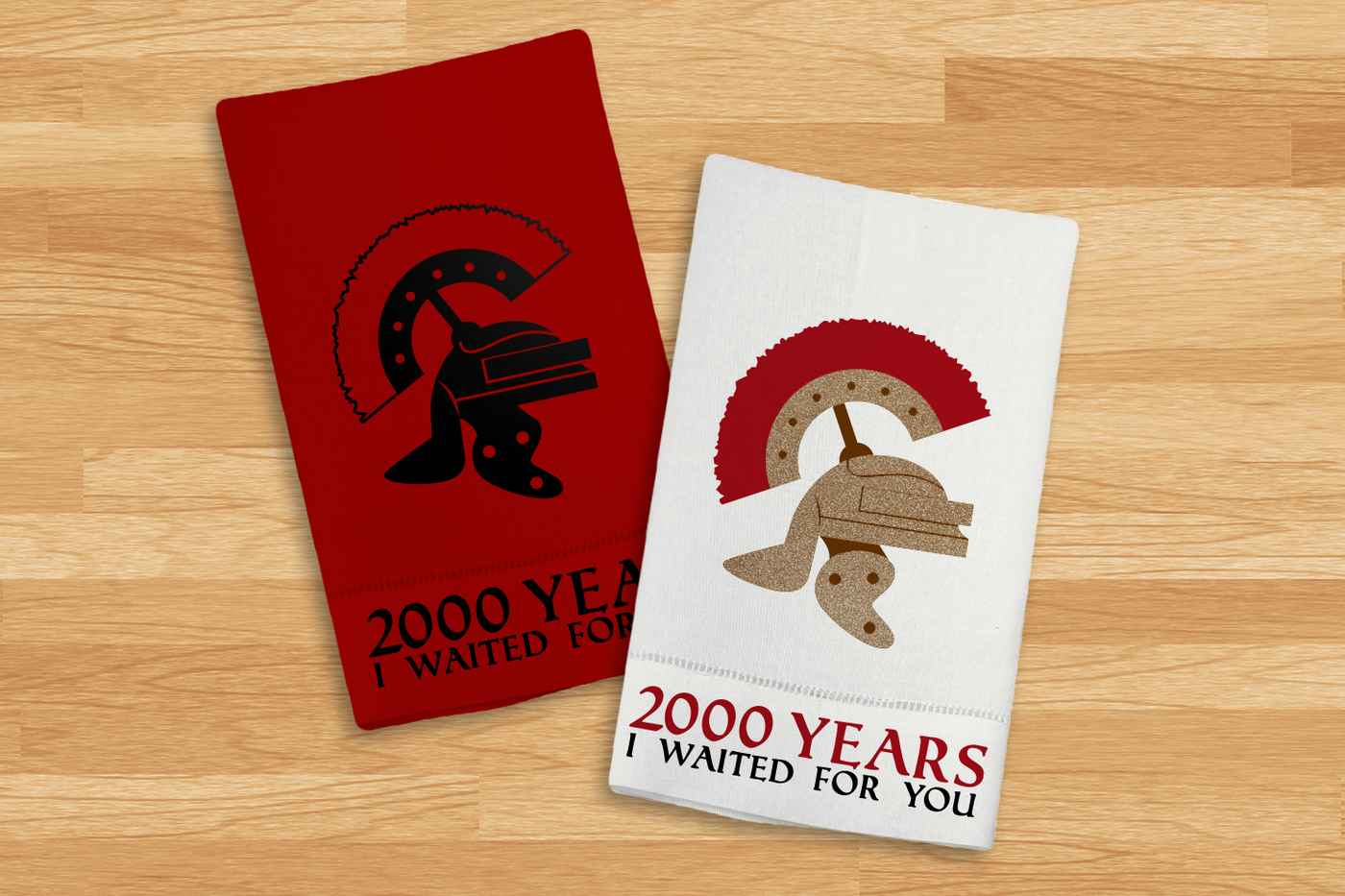 Two tea towels on a wood surface. Both have a Roman centurion helmet with the words "2000 years I waited for you."