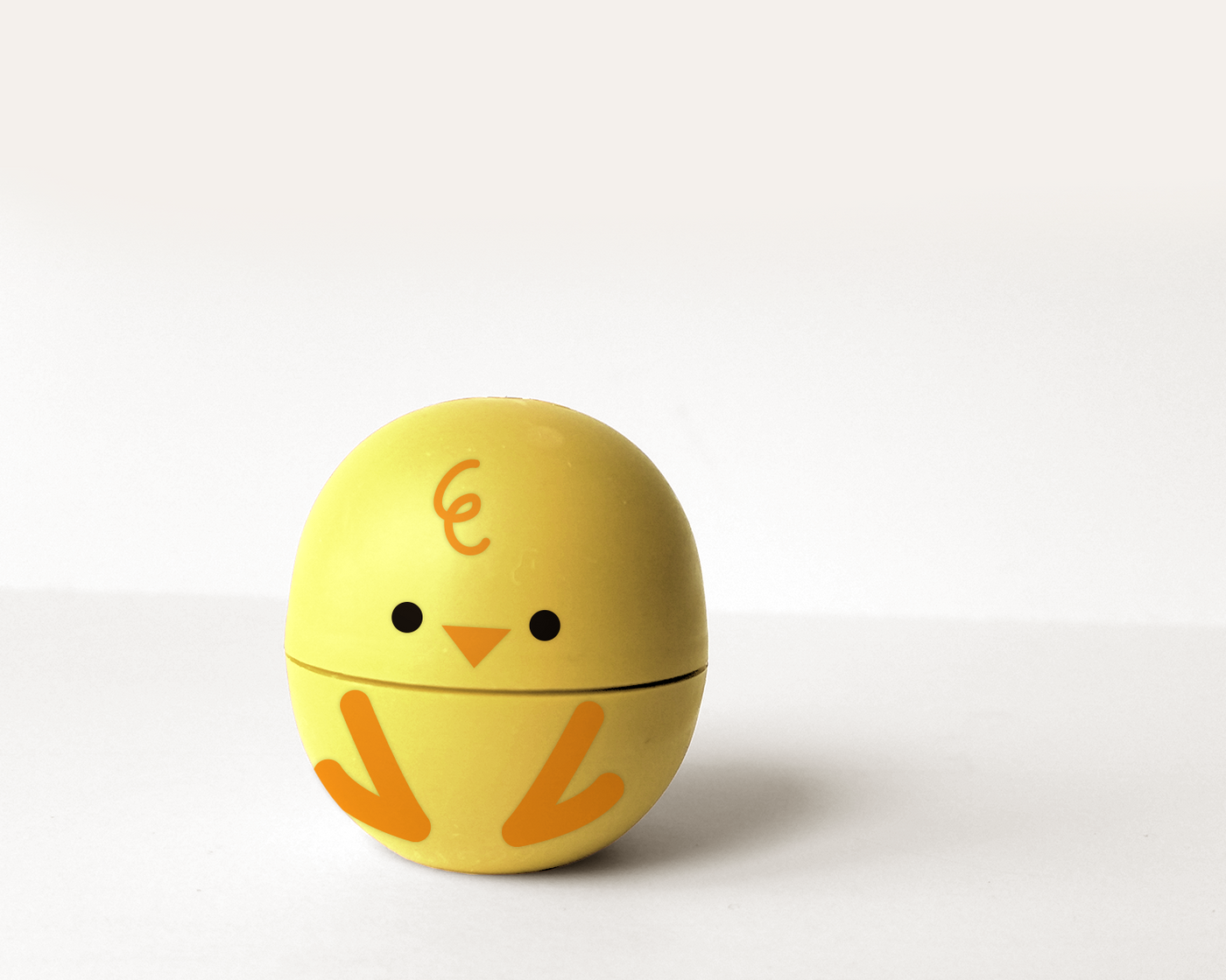Round lip balm container decorated to look like a baby chick.