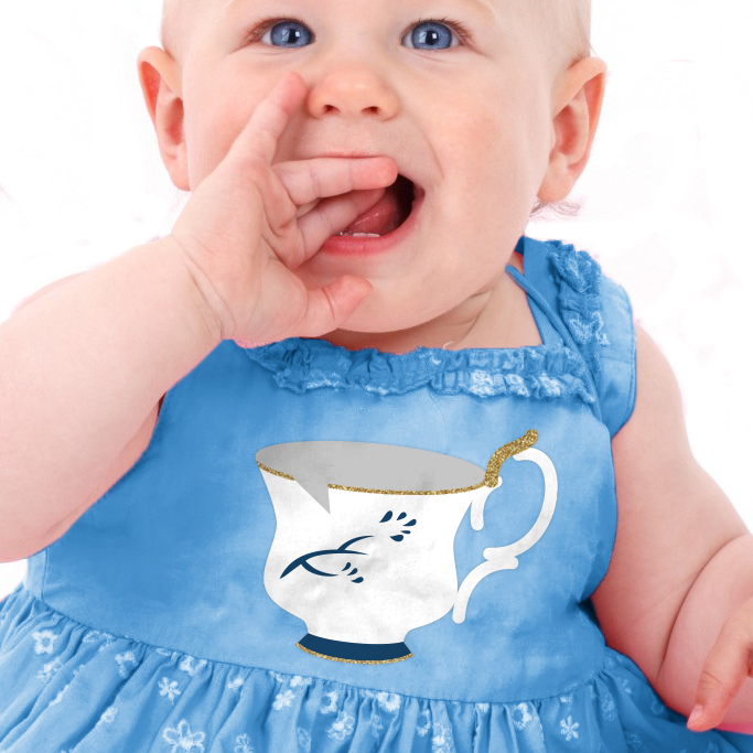 A white baby wears a blue dress. On the dress is a teacup design with a chip in the cup.