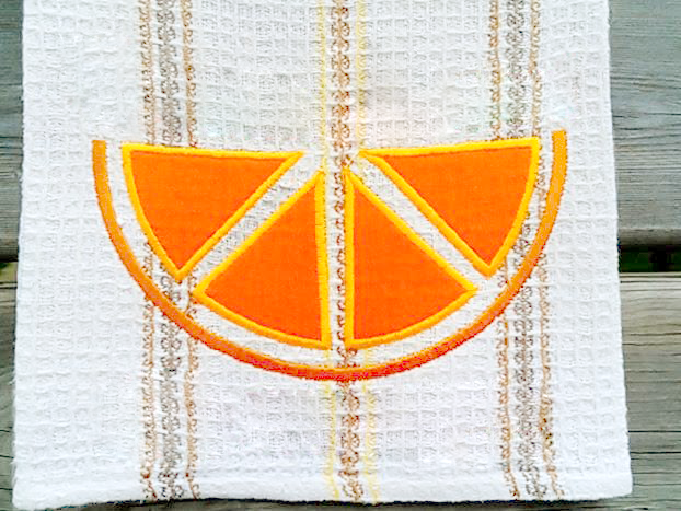 Tea towel with an applique citrus slice in orange.