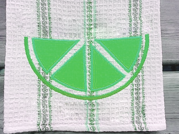 Tea towel with an applique citrus slice in green.