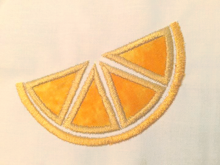 Off white fabric with an orange applique citrus slice.