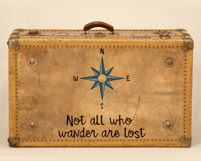 An old suitcase with a compass rose and the words "Not all who wander are lost"