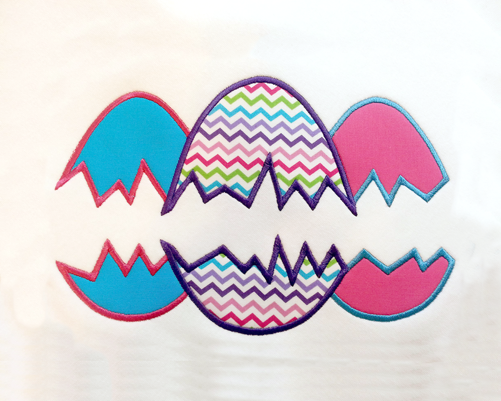 3 Applique Easter eggs with brightly colored applique fabrics and stitching. In the middle of the eggs are cracks creating a split in the middle for adding your own text.