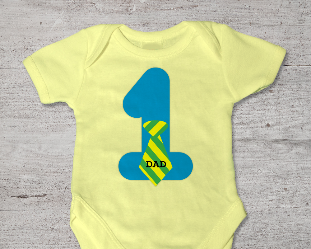 Yellow baby onesie with a large 1 on it. The number wears a striped tie that says "DAD"
