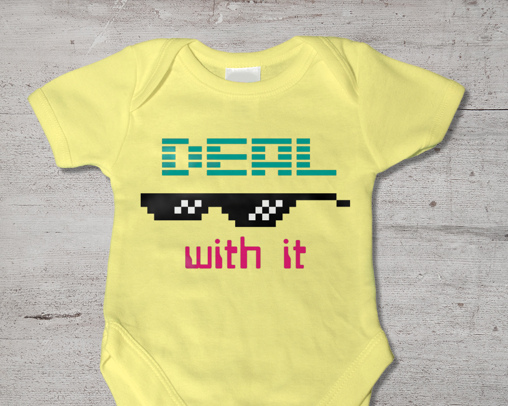 A yellow baby onesie with the words "Deal with it" in retro 80s lettering and pixel sunglasses.