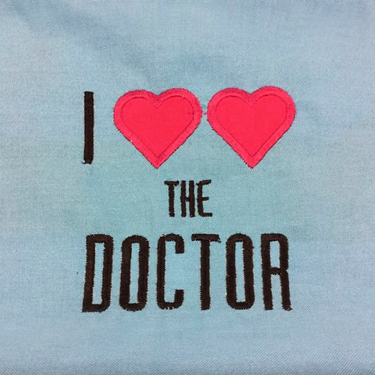 Fabric with embroidered phrase "I heart heart the doctor." The two hearts are applique.