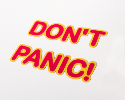 Letters with rounded edges in red with a yellow border made out of paper. Says "Don't Panic!"