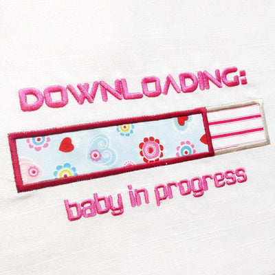 Applique design of a partially filled horizontal bar. Above and below are the words "Downloading: baby in progress"