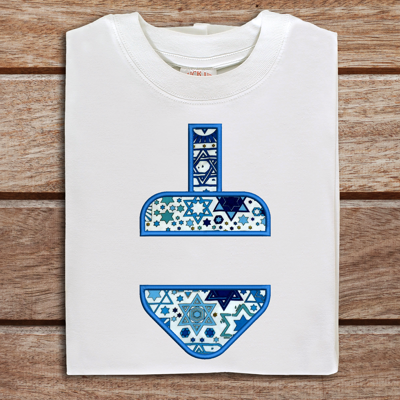 Folded tee with an applique dreidel design with a split in the middle.