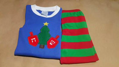 A pair of holiday jammies. The shirt is decorated with an applique of a Christmas tree with a dreidel on each side.