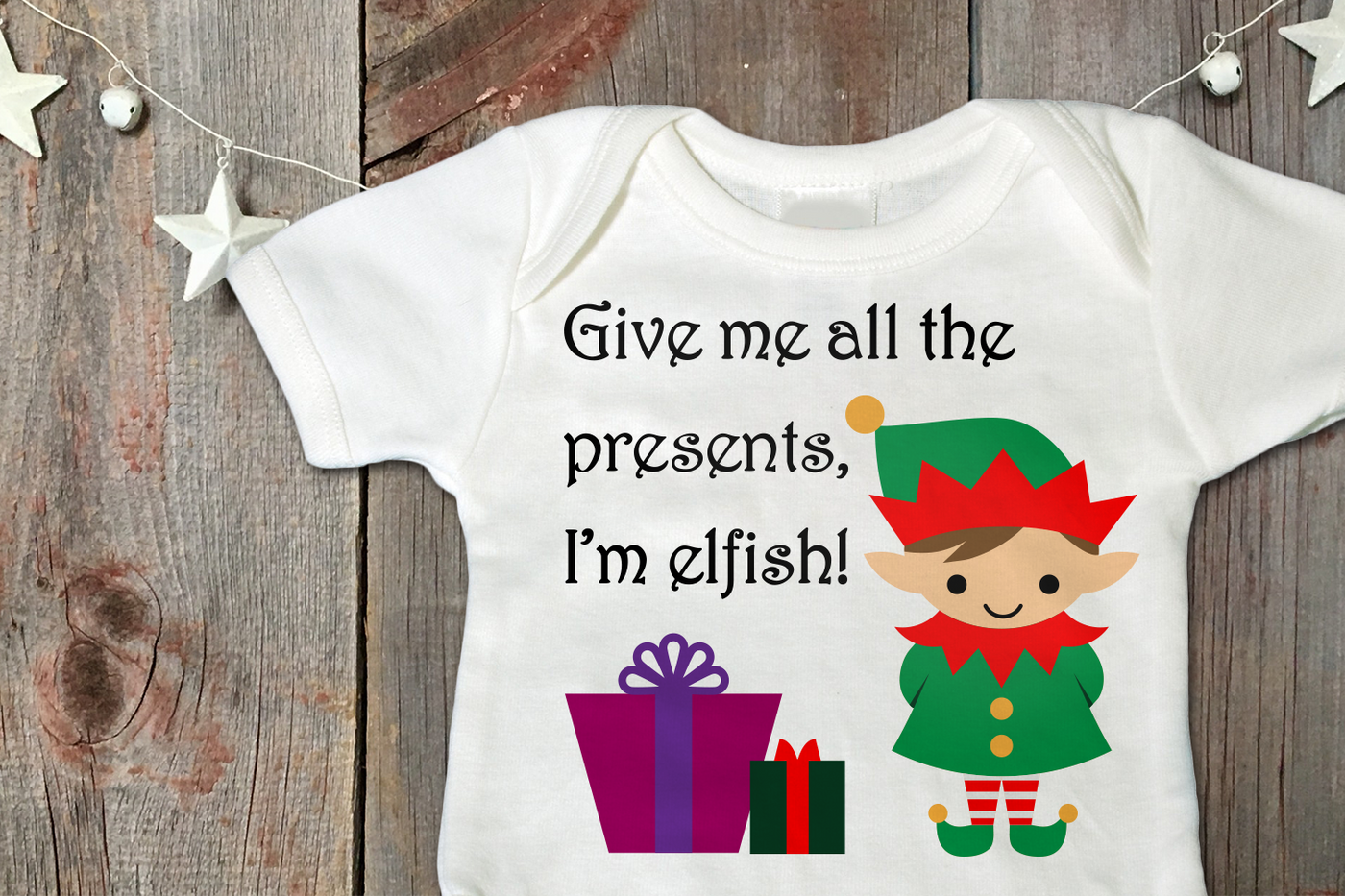 White onesie with a design of a cute elf with presents. It says "Give me all the presents, I'm elfish!"