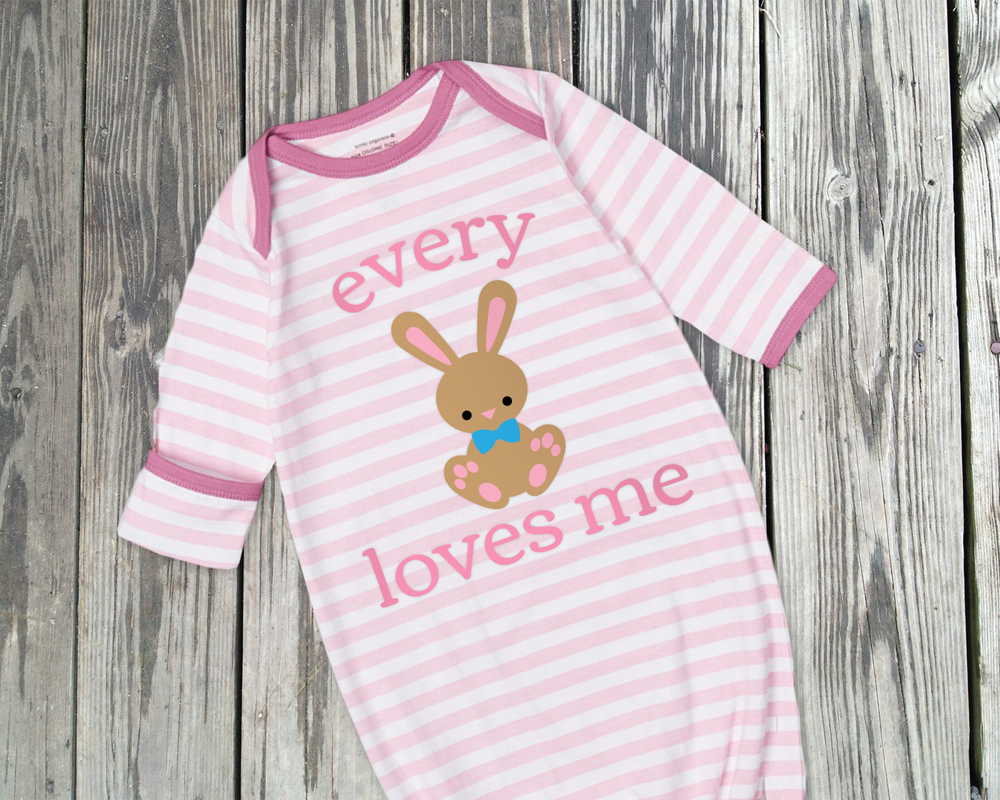 A pink an white striped baby sleep gown with a bunny wearing a bow tie. Around the bunny are the words "every" and "loves me" to complete the phrase "every [bunny] loves me"
