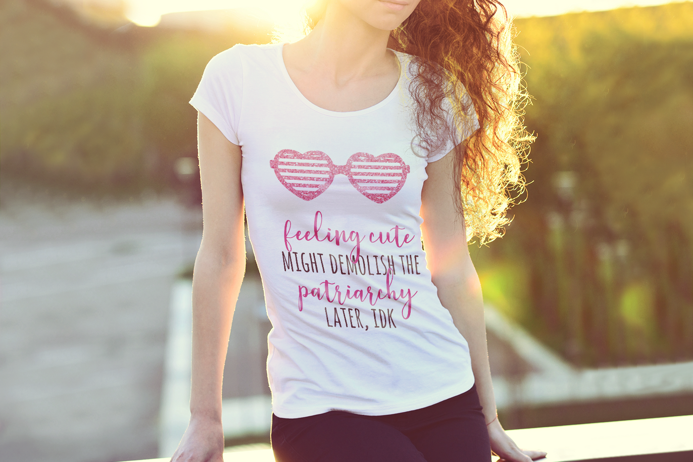 A white woman wearing a white tee. The tee has heart shaped shutter shades and the phrase "feeling cute might demolish the patriarchy later, IDK"