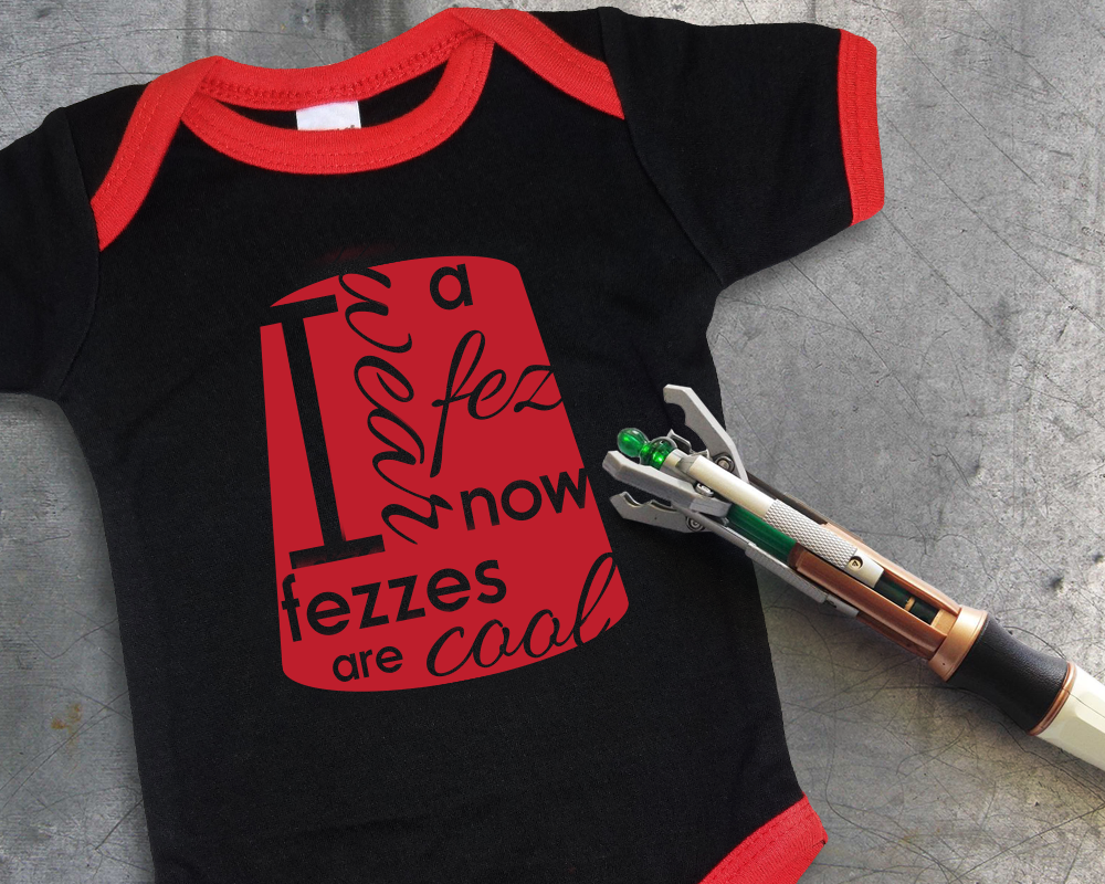 A red and black ringer onesie. The design has a red fez with knocked out words saying "I wear a fez now fezzes are cool"