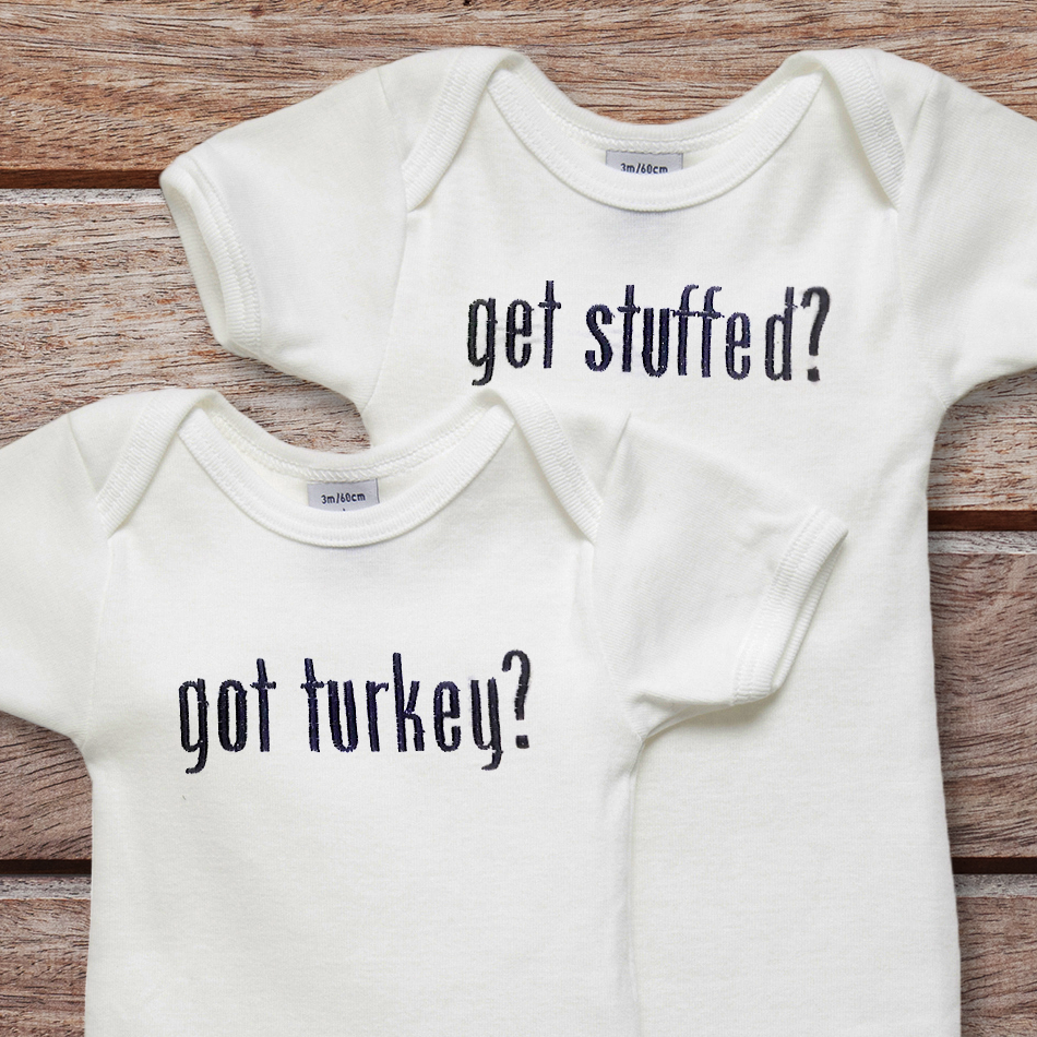 Two onesies. One is embroidered with "got turkey?" and the other is embroidered with "get stuffed?"